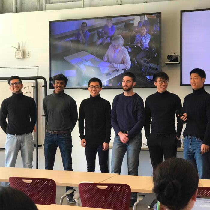 6 students standing at the front of the classroom during a presentation.